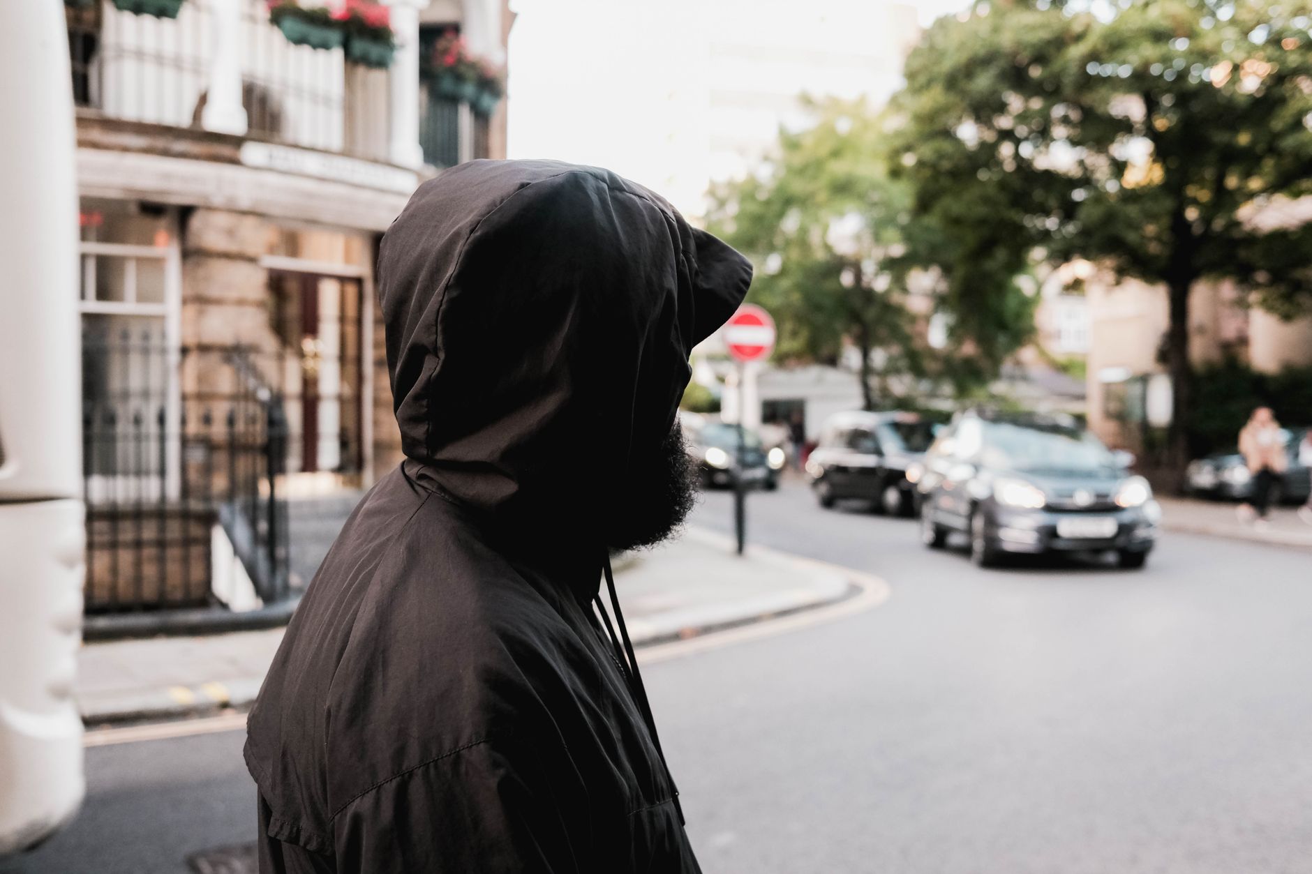 Hooded figure in anti-surveillance fashion on a dark British city street at night